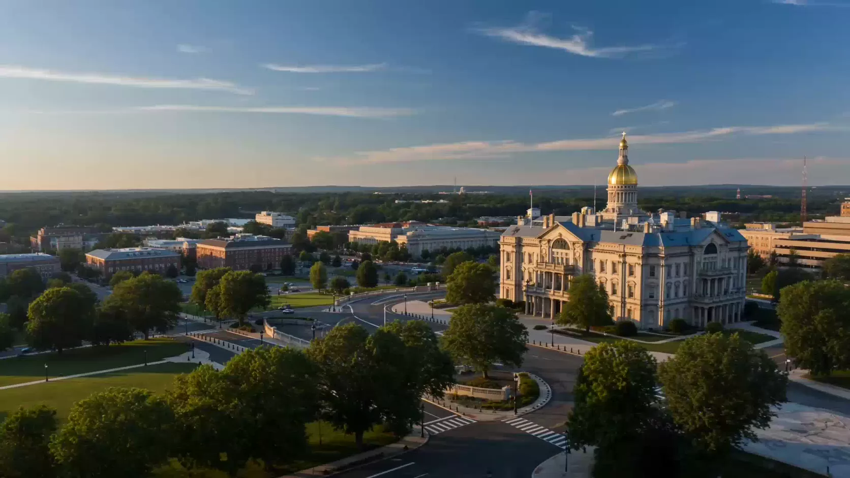Aerial view of a gold-domed state capitol at golden hour